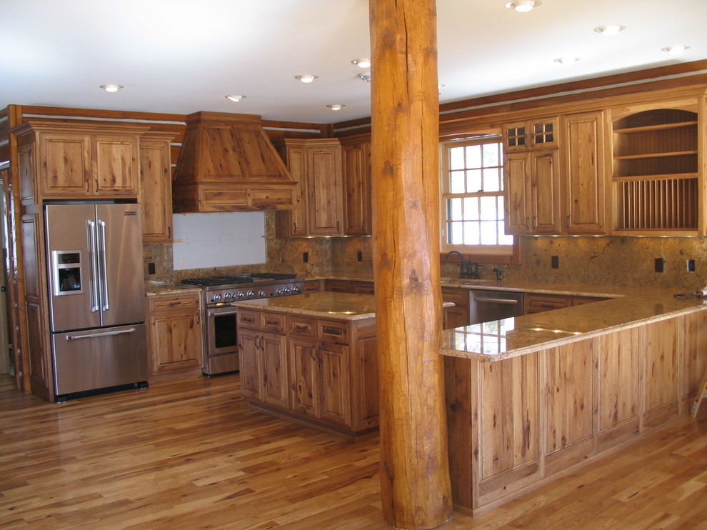 Inredning av ett rustikt avskilt, stort u-kök, med en undermonterad diskho, luckor med upphöjd panel, skåp i ljust trä, bänkskiva i kvarts, beige stänkskydd, stänkskydd i porslinskakel, rostfria vitvaror, ljust trägolv och en halv köksö