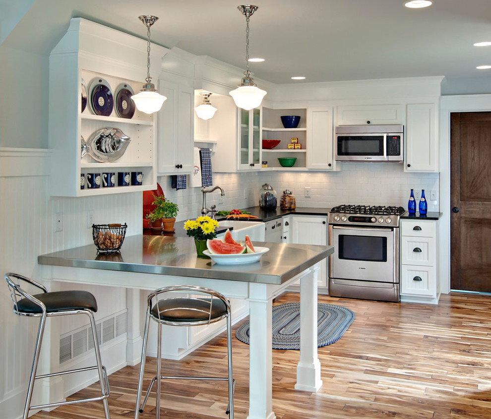 Inspiration for a contemporary kitchen remodel in Minneapolis with stainless steel appliances, stainless steel countertops, a farmhouse sink, recessed-panel cabinets, white cabinets, white backsplash and subway tile backsplash