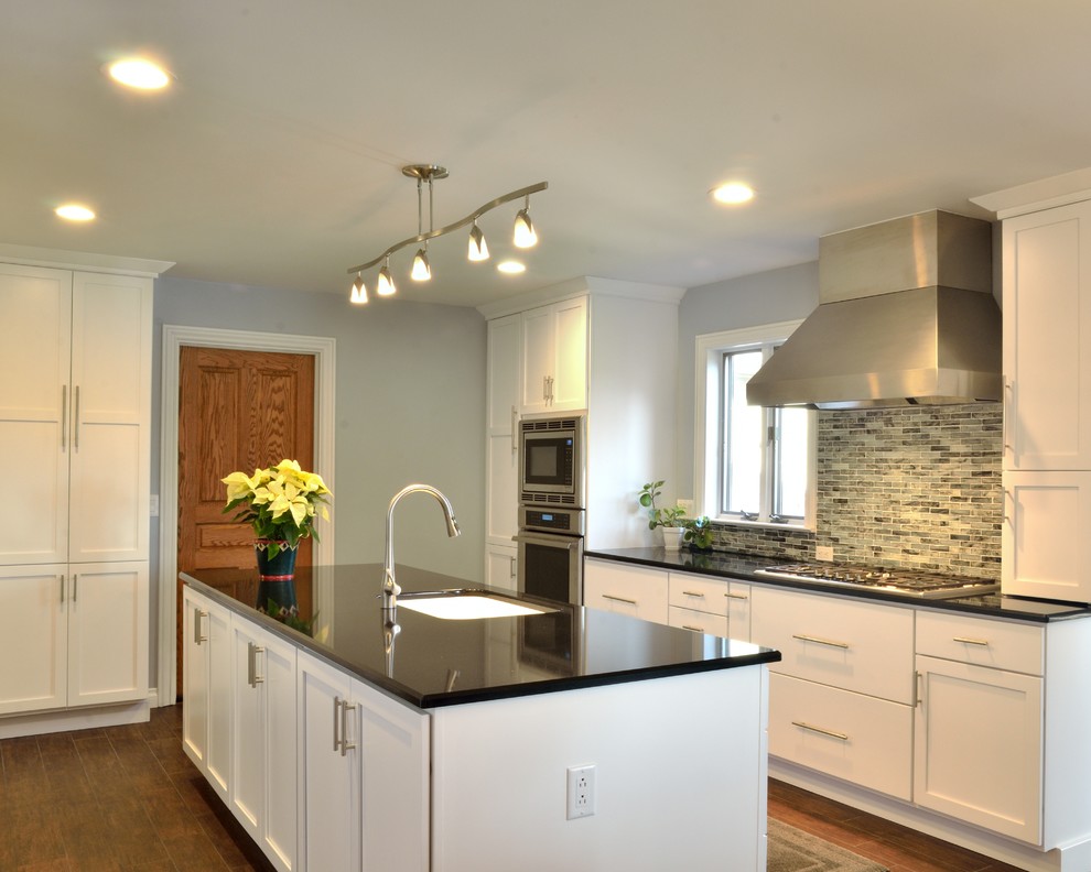 Example of a large island style galley porcelain tile eat-in kitchen design in Jackson with an integrated sink, flat-panel cabinets, white cabinets, quartzite countertops, gray backsplash, stainless steel appliances and an island