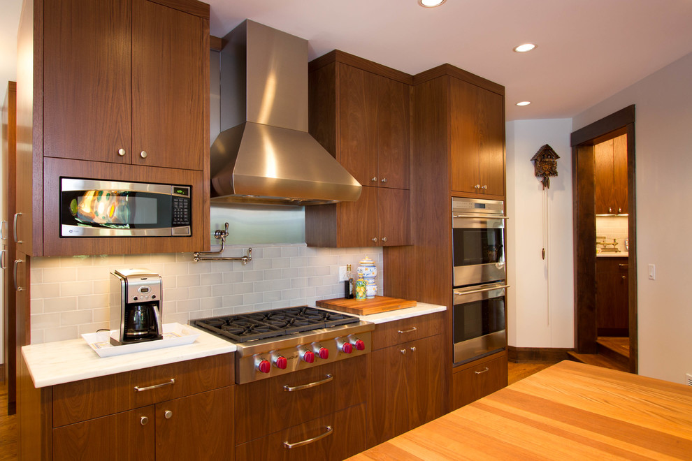 Photo of a contemporary kitchen in Minneapolis with flat-panel cabinets, dark wood cabinets, wood worktops, white splashback, metro tiled splashback and stainless steel appliances.