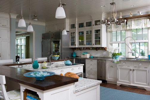Example of a large beach style dark wood floor and brown floor kitchen design in Other with an integrated sink, beaded inset cabinets, white cabinets, recycled glass countertops, blue backsplash, ceramic backsplash, stainless steel appliances and an island