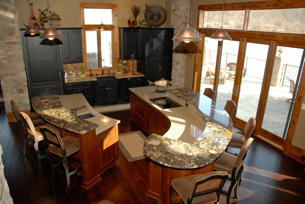 Idéer för att renovera ett mellanstort rustikt linjärt kök och matrum, med en enkel diskho, luckor med upphöjd panel, svarta skåp, beige stänkskydd, flera köksöar, stänkskydd i travertin, integrerade vitvaror, mörkt trägolv och brunt golv