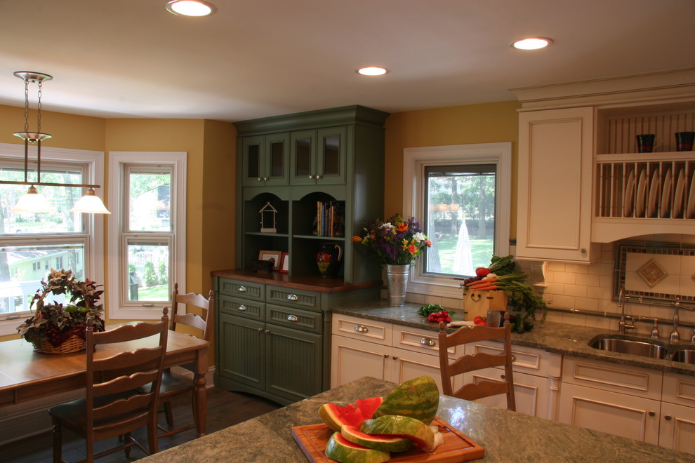 Exempel på ett avskilt, mellanstort lantligt u-kök, med en undermonterad diskho, luckor med infälld panel, beige skåp, granitbänkskiva, beige stänkskydd, stänkskydd i keramik, rostfria vitvaror, mellanmörkt trägolv och en köksö