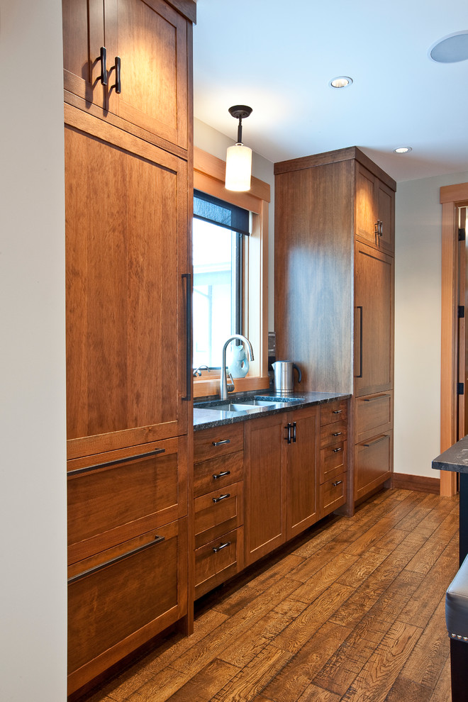 Ejemplo de cocina contemporánea de tamaño medio con armarios estilo shaker, puertas de armario de madera en tonos medios, encimera de laminado, electrodomésticos con paneles, suelo de madera en tonos medios y una isla