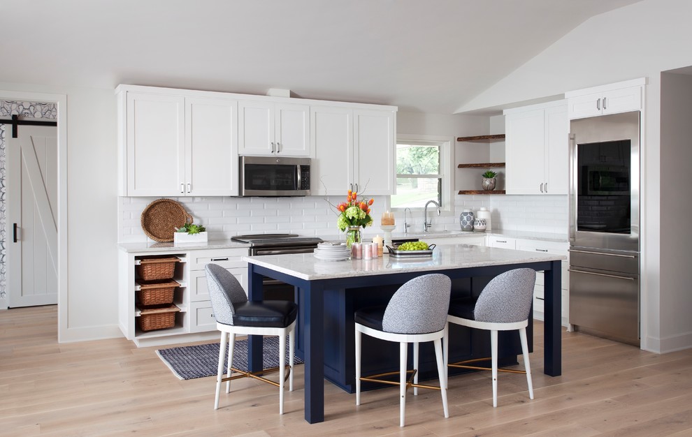 Exempel på ett mellanstort maritimt vit vitt kök, med en undermonterad diskho, skåp i shakerstil, blå skåp, bänkskiva i kvarts, vitt stänkskydd, stänkskydd i marmor, rostfria vitvaror, ljust trägolv, en köksö och brunt golv