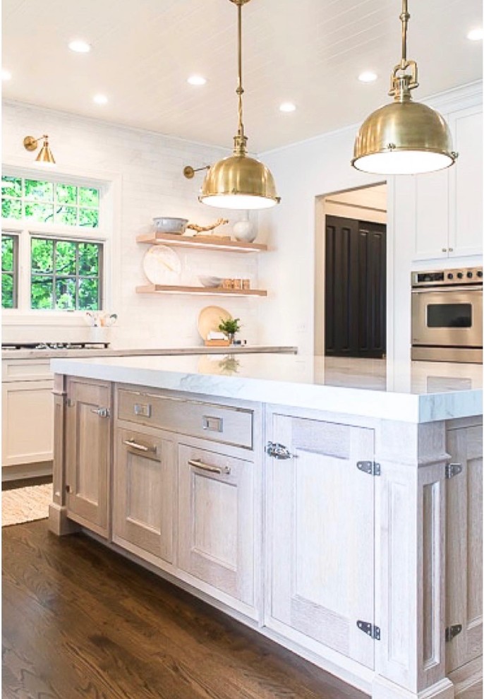 Mid-sized beach style u-shaped dark wood floor and brown floor eat-in kitchen photo in Milwaukee with an undermount sink, shaker cabinets, beige cabinets, marble countertops, gray backsplash, subway tile backsplash, stainless steel appliances, an island and white countertops