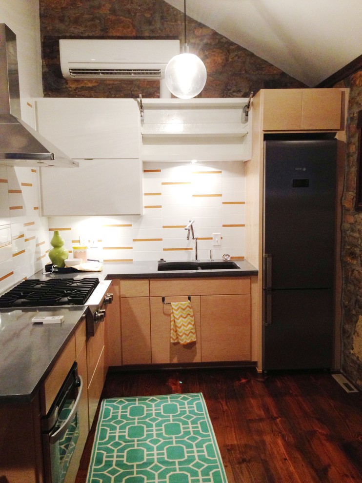 Bild på ett funkis kök, med en undermonterad diskho, släta luckor, bänkskiva i betong, vitt stänkskydd, stänkskydd i glaskakel och rostfria vitvaror