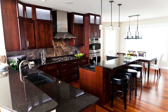 Foto på ett stort funkis kök, med en dubbel diskho, skåp i shakerstil, skåp i mellenmörkt trä, granitbänkskiva, brunt stänkskydd, stänkskydd i porslinskakel, rostfria vitvaror, mellanmörkt trägolv och en köksö