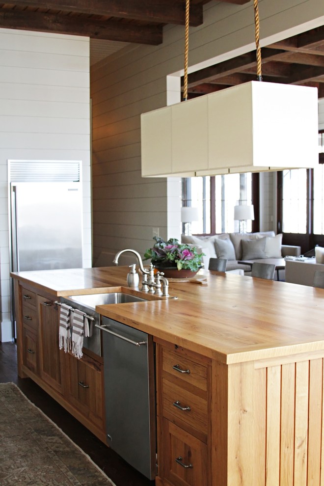 Foto de cocina costera con electrodomésticos de acero inoxidable, fregadero sobremueble, encimera de madera y puertas de armario de madera oscura