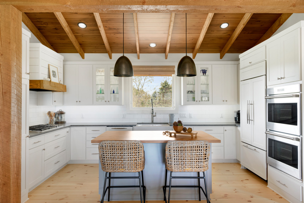 Inspiration for a mid-sized country u-shaped light wood floor and beige floor eat-in kitchen remodel in Minneapolis with a farmhouse sink, shaker cabinets, white cabinets, quartz countertops, white backsplash, subway tile backsplash, stainless steel appliances, an island and gray countertops