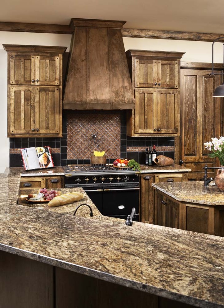 Foto di un cucina con isola centrale tradizionale con ante con riquadro incassato, ante in legno scuro, top in granito, paraspruzzi rosso e elettrodomestici neri