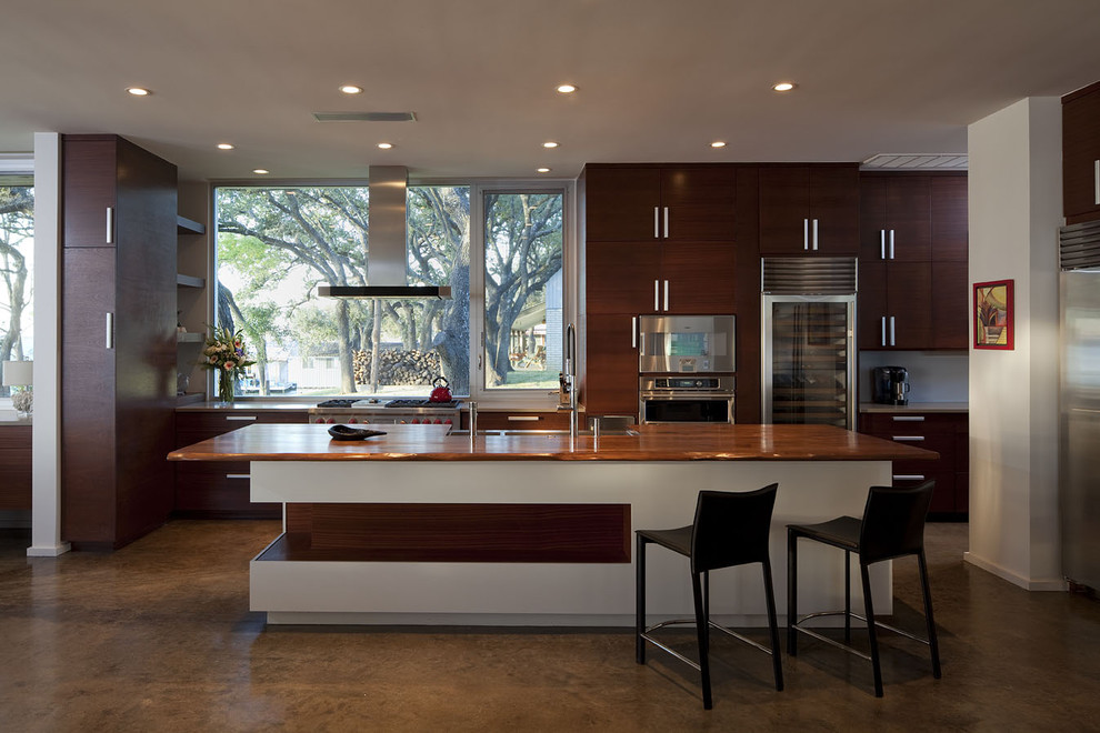 Exempel på ett stort modernt kök, med rostfria vitvaror, släta luckor, skåp i mörkt trä, träbänkskiva, en rustik diskho, betonggolv och en köksö