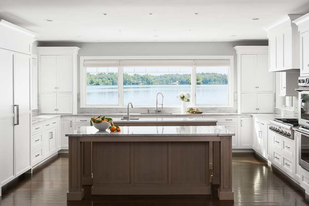 Design ideas for a large traditional u-shaped kitchen in Boston with a submerged sink, flat-panel cabinets, white cabinets, quartz worktops, integrated appliances, dark hardwood flooring, multiple islands and brown floors.