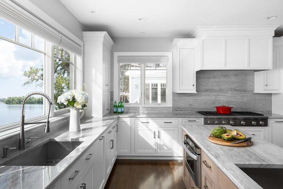 Exempel på ett klassiskt kök, med en undermonterad diskho, vita skåp, bänkskiva i kvartsit, rostfria vitvaror, mellanmörkt trägolv och en köksö