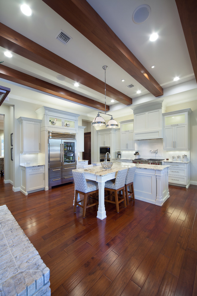 This is an example of a large rural u-shaped kitchen/diner in Orlando with a single-bowl sink, shaker cabinets, white cabinets, granite worktops, white splashback, stone tiled splashback, stainless steel appliances, medium hardwood flooring and multiple islands.