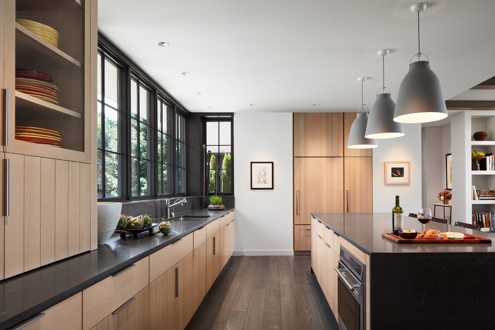 Свежая идея для дизайна: параллельная кухня в стиле неоклассика (современная классика) с одинарной мойкой, светлыми деревянными фасадами, темным паркетным полом, островом и коричневым полом - отличное фото интерьера