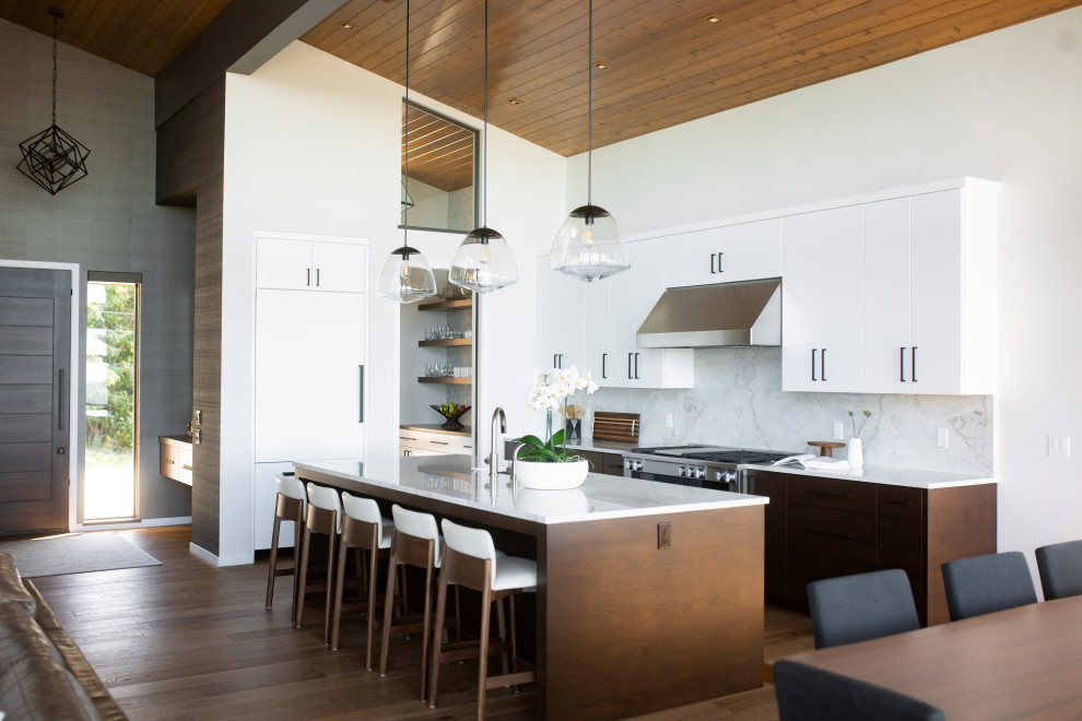 Inspiration for a contemporary l-shaped kitchen/diner in Grand Rapids with flat-panel cabinets, white cabinets, white splashback, stone slab splashback, an island, brown floors, white worktops, a wood ceiling, a submerged sink, engineered stone countertops, integrated appliances and medium hardwood flooring.