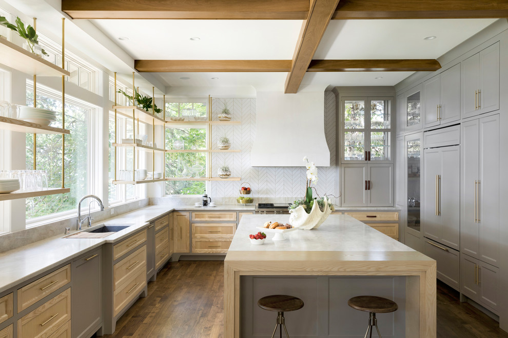 Cottage u-shaped medium tone wood floor and brown floor kitchen photo in Minneapolis with an undermount sink, recessed-panel cabinets, gray cabinets, white backsplash, paneled appliances, an island, white countertops and window backsplash