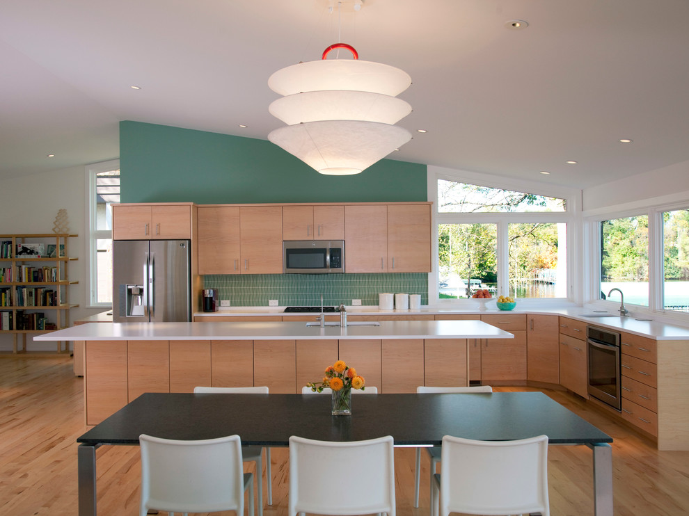 Contemporary l-shaped kitchen/diner in Minneapolis with a submerged sink, flat-panel cabinets, light wood cabinets, green splashback, stainless steel appliances, light hardwood flooring and an island.