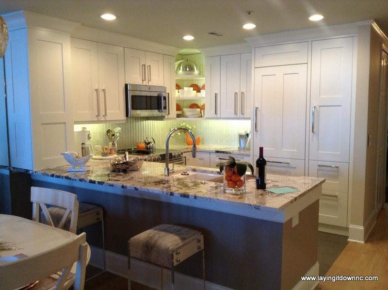 Modern inredning av ett litet kök, med en undermonterad diskho, släta luckor, vita skåp, granitbänkskiva, vitt stänkskydd, stänkskydd i glaskakel, rostfria vitvaror och klinkergolv i porslin