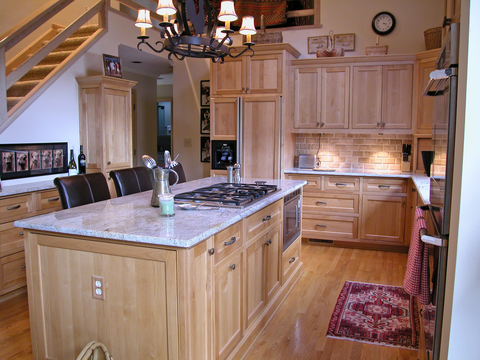 Example of a classic u-shaped eat-in kitchen design in Charlotte with an undermount sink, flat-panel cabinets, light wood cabinets, granite countertops, beige backsplash, terra-cotta backsplash and stainless steel appliances