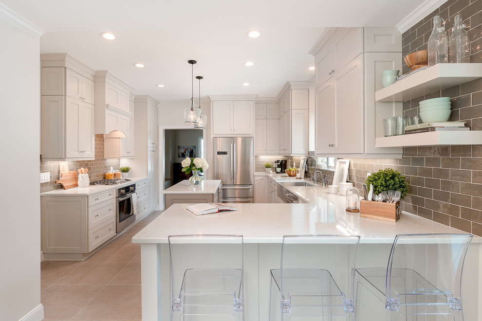 Example of a mid-sized transitional u-shaped ceramic tile and beige floor kitchen design in Charlotte with a farmhouse sink, shaker cabinets, quartz countertops, brown backsplash, ceramic backsplash, stainless steel appliances, an island, white countertops and white cabinets