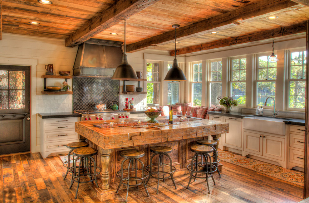 Example of a large mountain style l-shaped dark wood floor and brown floor eat-in kitchen design in Minneapolis with a farmhouse sink, beaded inset cabinets, white cabinets, soapstone countertops, white backsplash, an island and black countertops