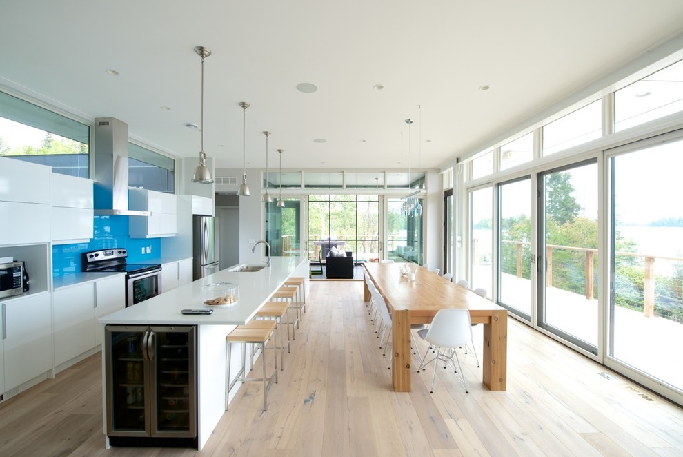 This is an example of a modern galley open plan kitchen in Other with blue splashback and glass sheet splashback.