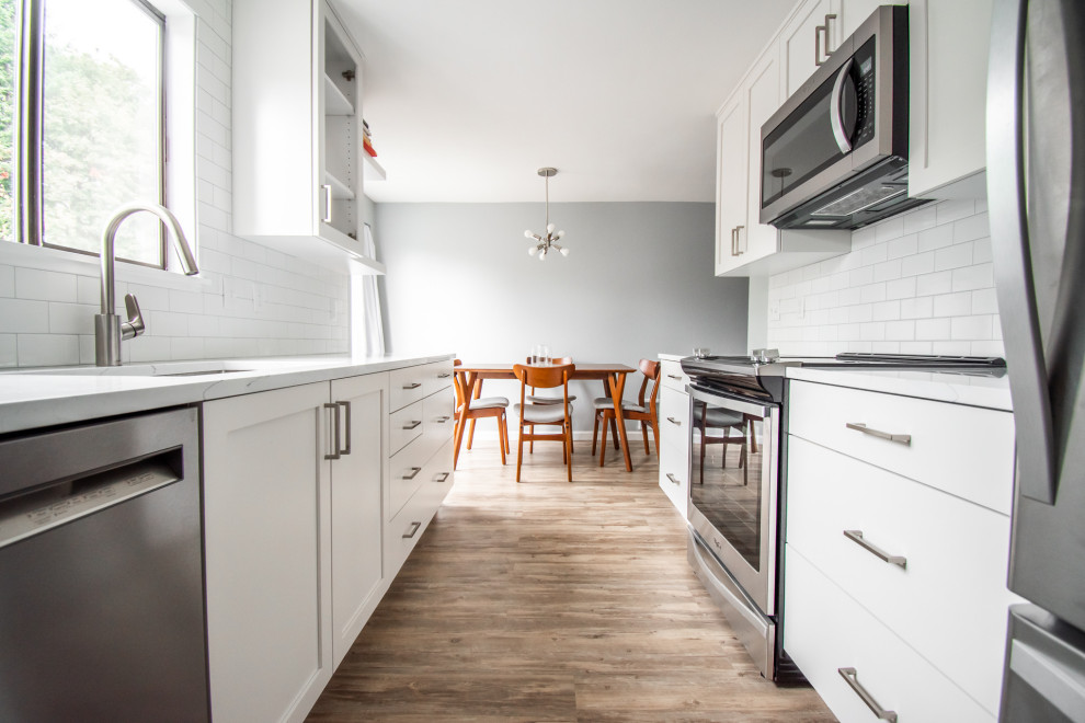 Idéer för att renovera ett litet funkis vit vitt kök, med en undermonterad diskho, luckor med glaspanel, vita skåp, vitt stänkskydd, stänkskydd i keramik, rostfria vitvaror, mellanmörkt trägolv, brunt golv och bänkskiva i kvartsit