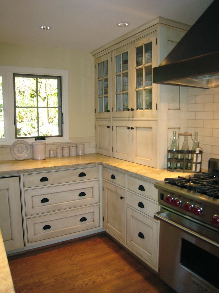 Eat-in kitchen - large traditional l-shaped dark wood floor and brown floor eat-in kitchen idea in Portland with a farmhouse sink, glass-front cabinets, white cabinets, marble countertops, white backsplash, subway tile backsplash, stainless steel appliances, an island and white countertops