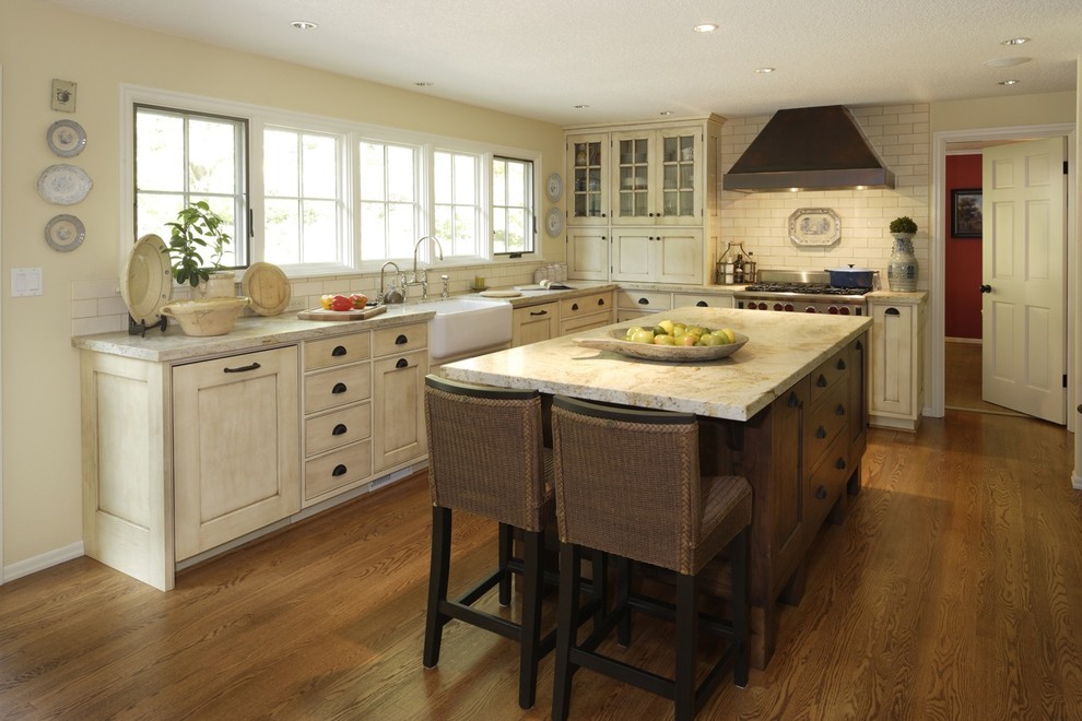 Example of a large country l-shaped dark wood floor and brown floor eat-in kitchen design in Portland with a farmhouse sink, white cabinets, white backsplash, subway tile backsplash, marble countertops, an island, stainless steel appliances, white countertops and beaded inset cabinets