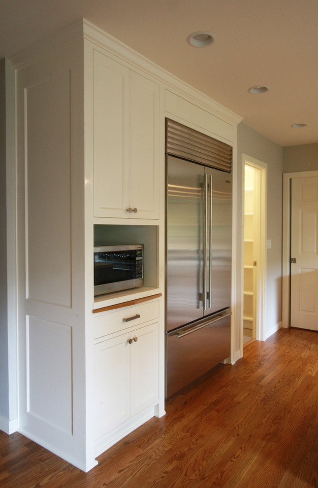Example of a large transitional l-shaped medium tone wood floor and brown floor open concept kitchen design in Portland with shaker cabinets, white cabinets, white backsplash, stainless steel appliances and an island