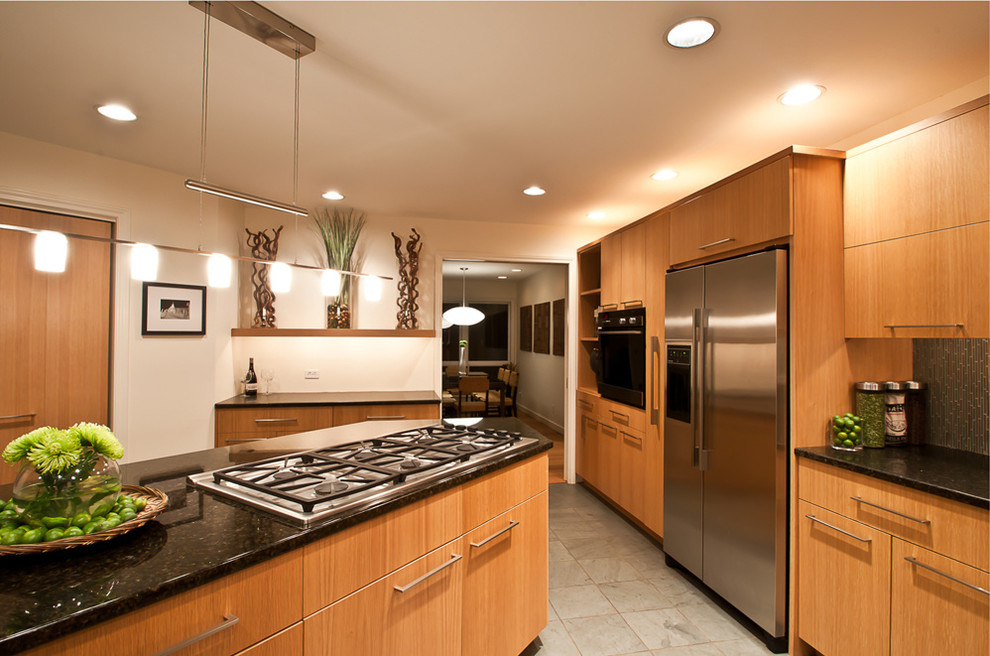 Imagen de cocina contemporánea abierta con fregadero bajoencimera, armarios con paneles lisos, puertas de armario de madera clara, encimera de granito, salpicadero gris y electrodomésticos de acero inoxidable