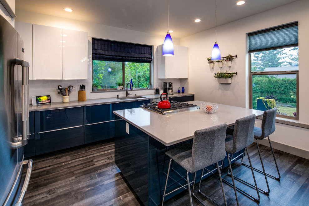 Exempel på ett mellanstort modernt grå grått kök, med en undermonterad diskho, släta luckor, bänkskiva i kvartsit, vitt stänkskydd, stänkskydd i tunnelbanekakel, rostfria vitvaror, laminatgolv, en köksö, blå skåp och brunt golv