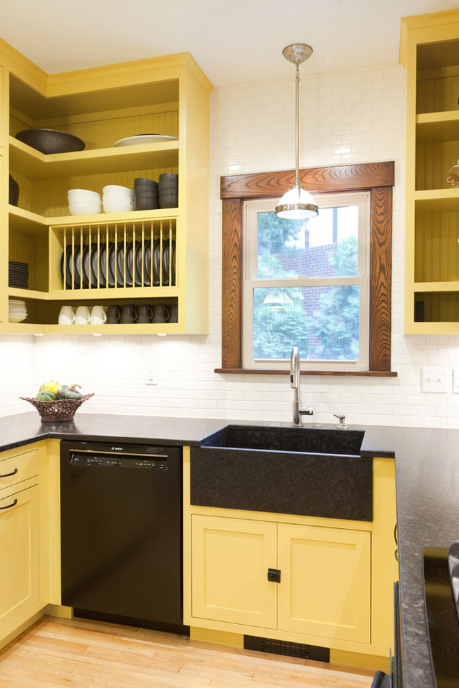 ミネアポリスにある高級な中くらいなトラディショナルスタイルのおしゃれなキッチン (エプロンフロントシンク、フラットパネル扉のキャビネット、黄色いキャビネット、御影石カウンター、白いキッチンパネル、セラミックタイルのキッチンパネル、黒い調理設備、淡色無垢フローリング、アイランドなし) の写真