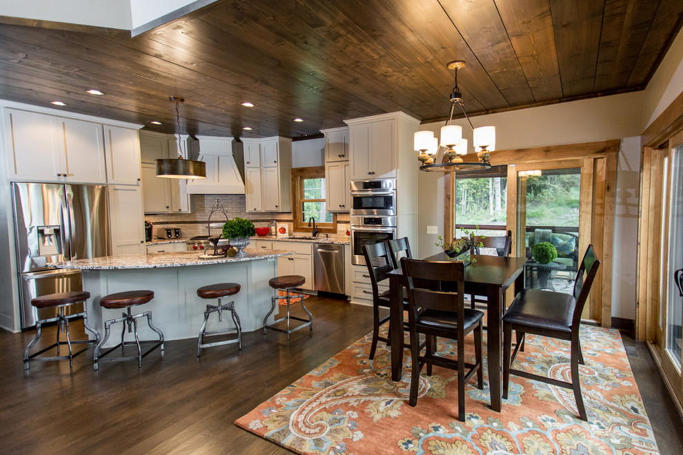 This is an example of a rustic u-shaped kitchen/diner in Minneapolis with a submerged sink, shaker cabinets, grey cabinets, granite worktops, multi-coloured splashback, metro tiled splashback, stainless steel appliances, dark hardwood flooring and an island.