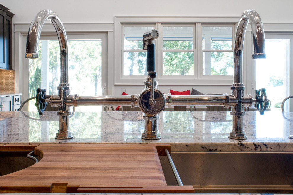 Example of a large transitional l-shaped light wood floor eat-in kitchen design in Milwaukee with a single-bowl sink, recessed-panel cabinets, blue cabinets, granite countertops, metallic backsplash, metal backsplash, paneled appliances and an island