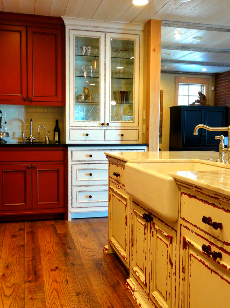 Bild på ett mellanstort lantligt kök, med en rustik diskho, luckor med profilerade fronter, röda skåp, marmorbänkskiva, vitt stänkskydd, stänkskydd i keramik, rostfria vitvaror, mellanmörkt trägolv och en köksö