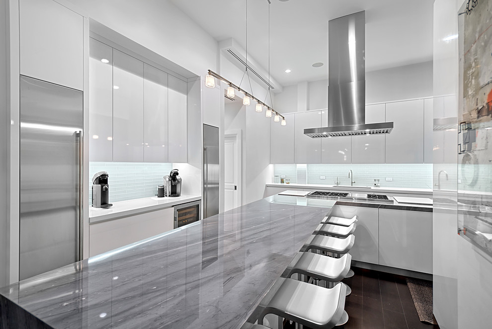 Example of a mid-sized minimalist u-shaped dark wood floor and brown floor eat-in kitchen design in Chicago with an undermount sink, flat-panel cabinets, white cabinets, marble countertops, white backsplash, mosaic tile backsplash, stainless steel appliances, an island and gray countertops