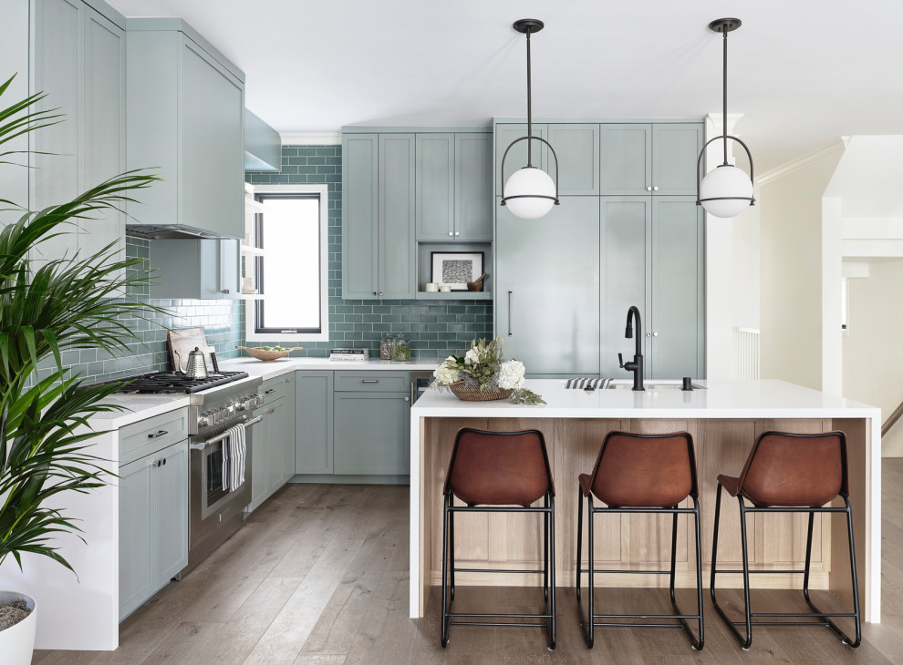 Inspiration for a mid-sized transitional l-shaped medium tone wood floor and brown floor open concept kitchen remodel in San Francisco with an undermount sink, shaker cabinets, green cabinets, quartz countertops, green backsplash, ceramic backsplash, an island, white countertops and paneled appliances