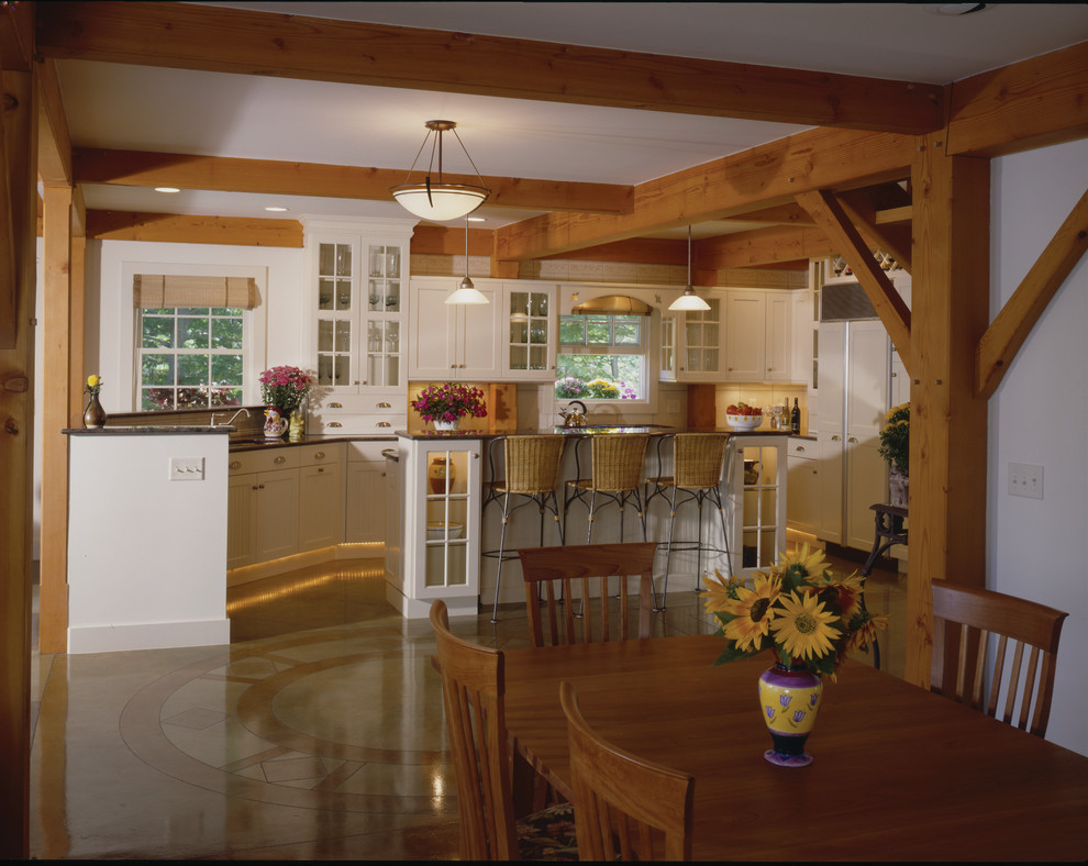 Foto di un cucina con isola centrale stile americano con ante bianche, top in granito, elettrodomestici da incasso e pavimento in cemento