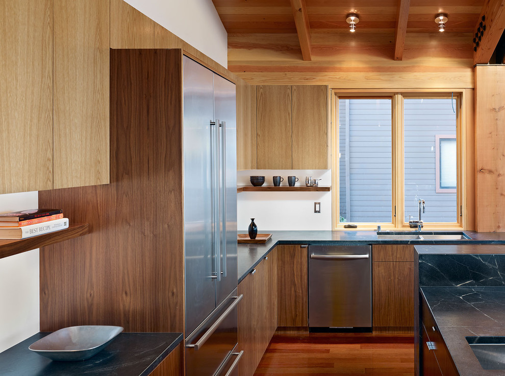 Пример оригинального дизайна: кухня в современном стиле с двойной мойкой, плоскими фасадами, техникой из нержавеющей стали, фасадами цвета дерева среднего тона, столешницей из талькохлорита и окном