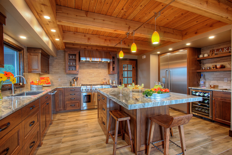 シアトルにあるラスティックスタイルのおしゃれなキッチン (アンダーカウンターシンク、中間色木目調キャビネット、ベージュキッチンパネル、シルバーの調理設備、茶色い床、マルチカラーのキッチンカウンター、窓) の写真