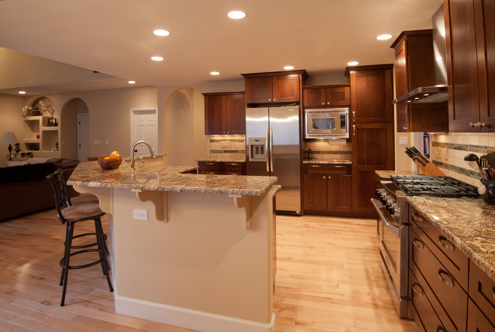 Mid-sized transitional l-shaped light wood floor and beige floor eat-in kitchen photo in Denver with an undermount sink, shaker cabinets, dark wood cabinets, granite countertops, beige backsplash, stone tile backsplash, stainless steel appliances and no island