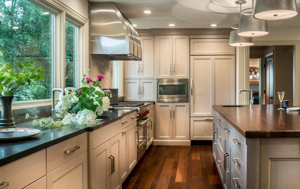 Eat-in kitchen - large transitional l-shaped medium tone wood floor eat-in kitchen idea in Chicago with an undermount sink, flat-panel cabinets, gray cabinets, granite countertops, gray backsplash, stone tile backsplash, paneled appliances and an island