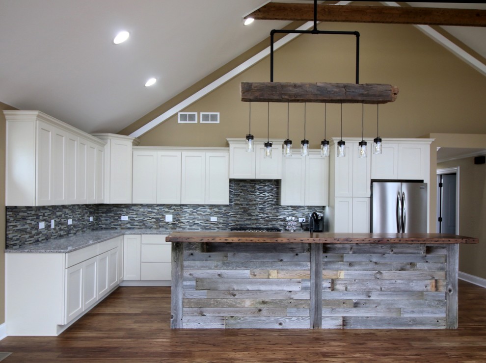 Design ideas for a large rustic l-shaped open plan kitchen in Chicago with a submerged sink, recessed-panel cabinets, white cabinets, engineered stone countertops, grey splashback, ceramic splashback, stainless steel appliances, medium hardwood flooring and an island.