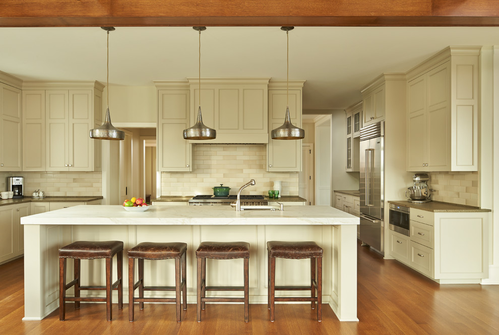 Exempel på ett stort klassiskt kök, med rostfria vitvaror, mellanmörkt trägolv, en köksö, luckor med infälld panel, beige skåp och beige stänkskydd