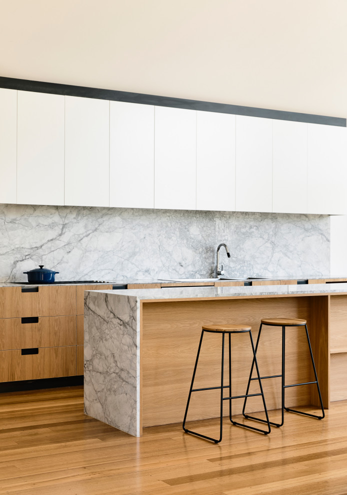 Immagine di una cucina design con ante lisce, ante bianche, paraspruzzi grigio, paraspruzzi in lastra di pietra, pavimento in legno massello medio, pavimento marrone e top grigio