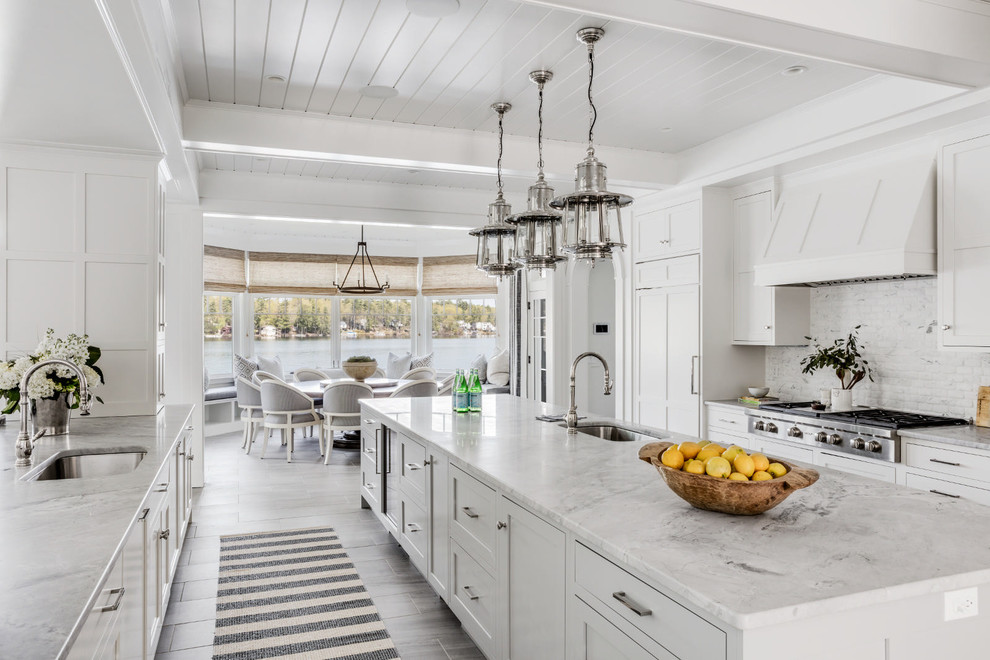 Beach style eat-in kitchen photo in Los Angeles with an undermount sink, shaker cabinets, white cabinets, marble countertops, white backsplash, marble backsplash, paneled appliances and an island