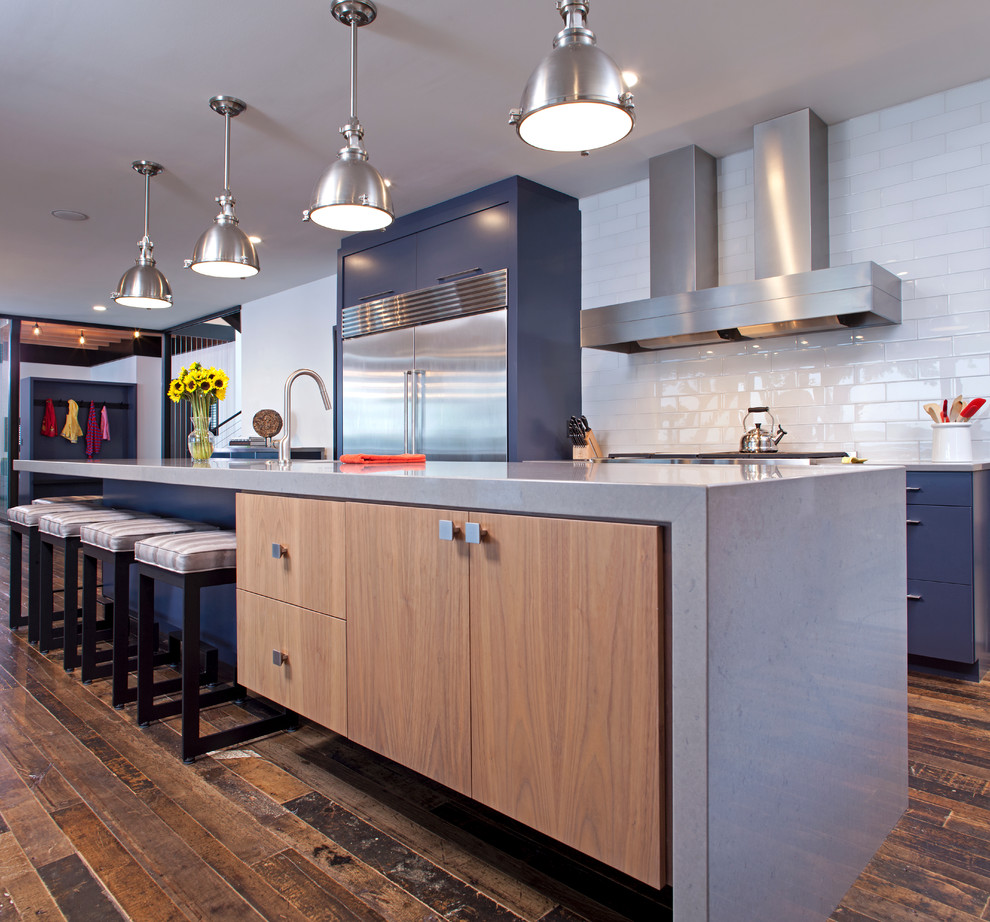 Example of a trendy u-shaped medium tone wood floor eat-in kitchen design in Minneapolis with an undermount sink, medium tone wood cabinets, quartzite countertops, white backsplash, subway tile backsplash, stainless steel appliances and an island